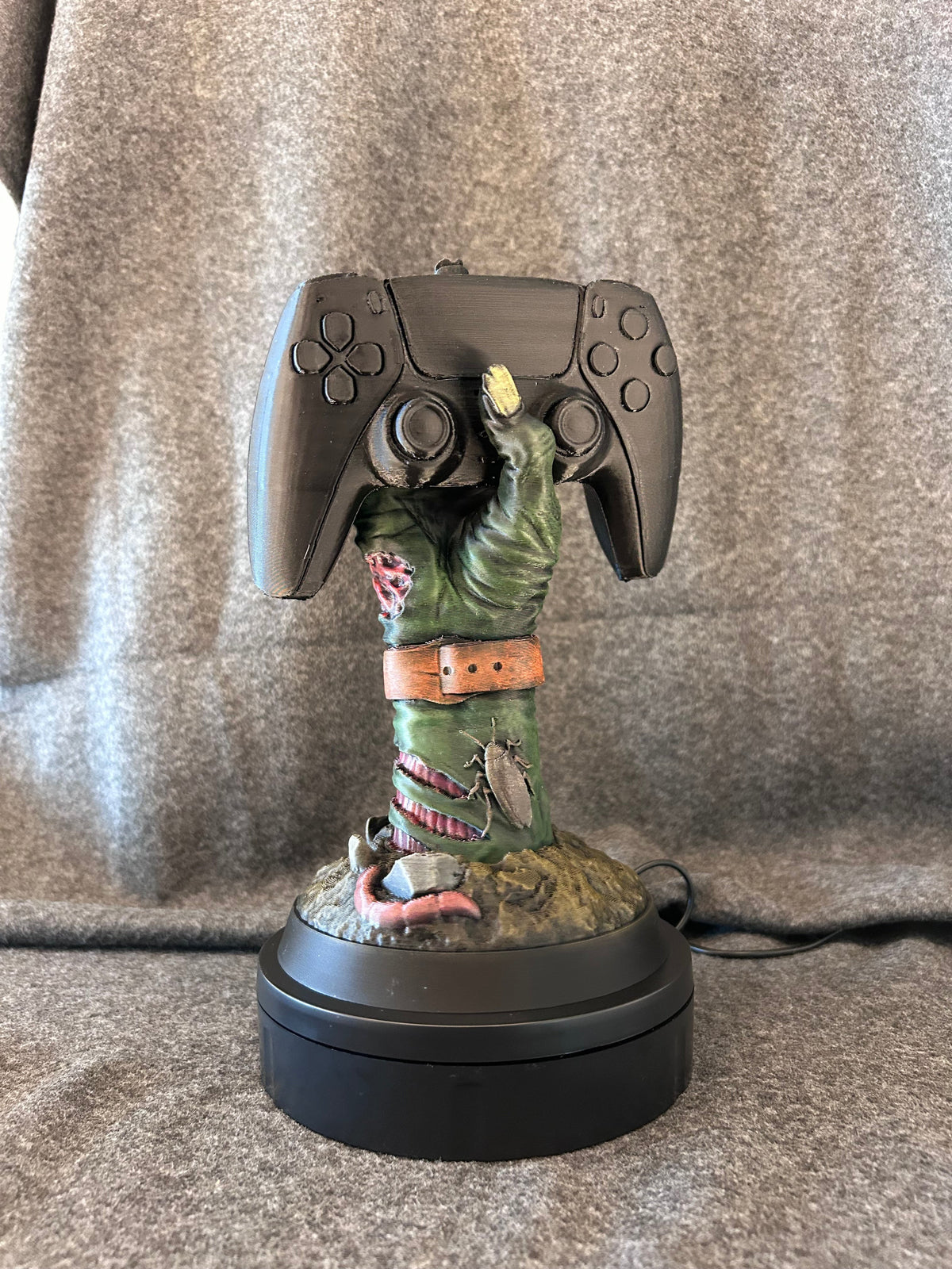 Hand-painted zombie hand controller stand gripping a game controller.