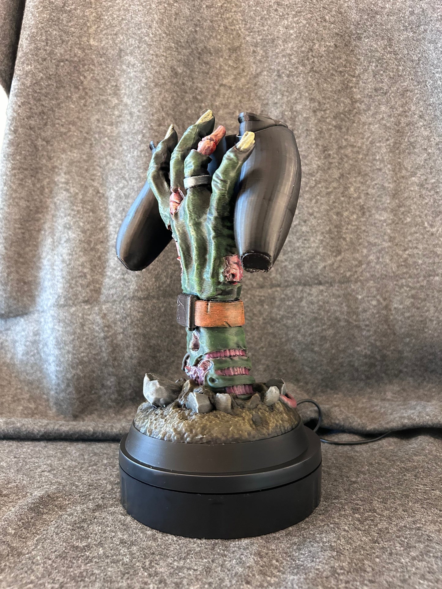 The zombie hand stand on its own, rising from grave dirt with a leather watch strap at the wrist.