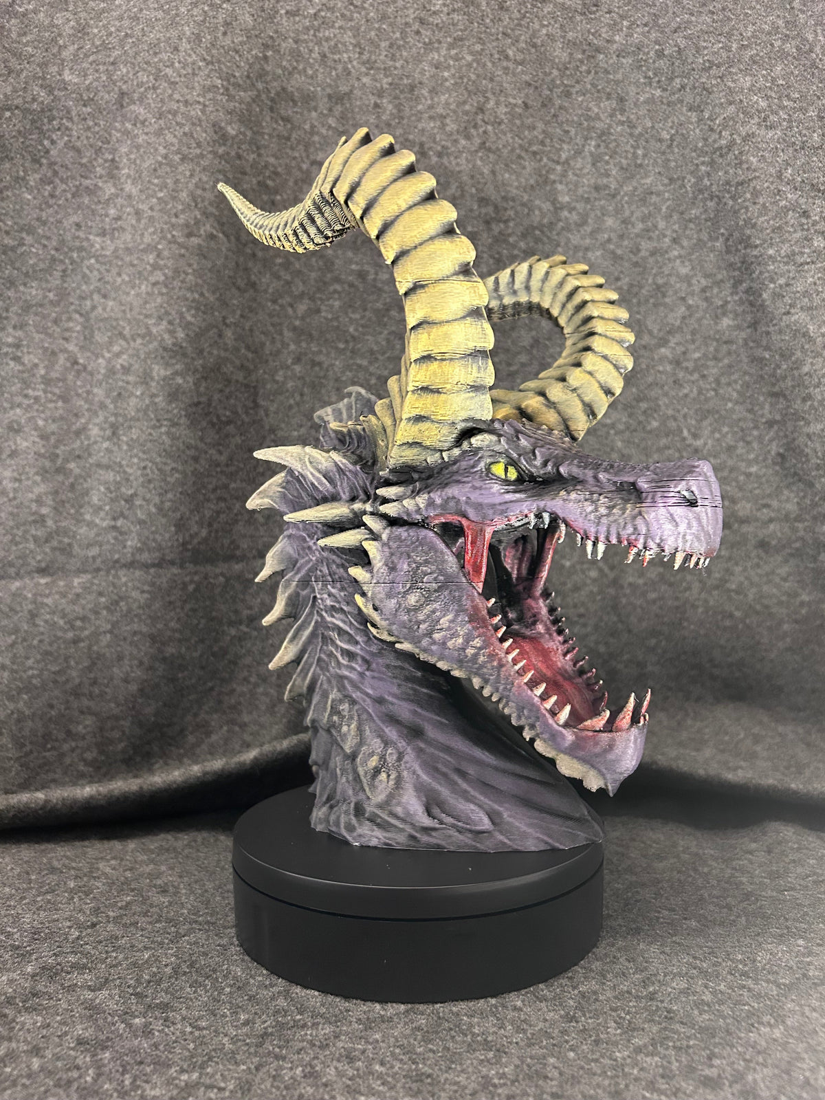 Side view of the Duskmaw dragon bust showing the ribbed yellow horns curling forward.