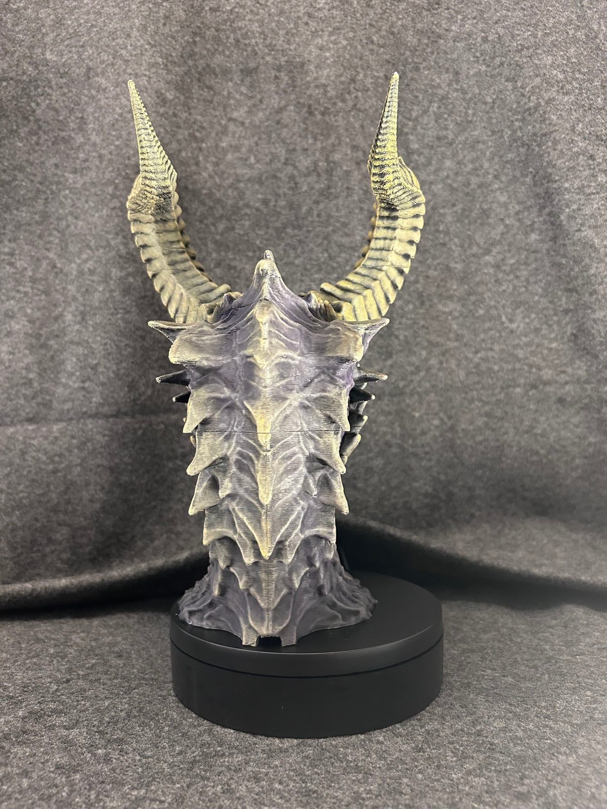 The Duskmaw dragon bust on its weighted base, showing the spined frill along the neck.