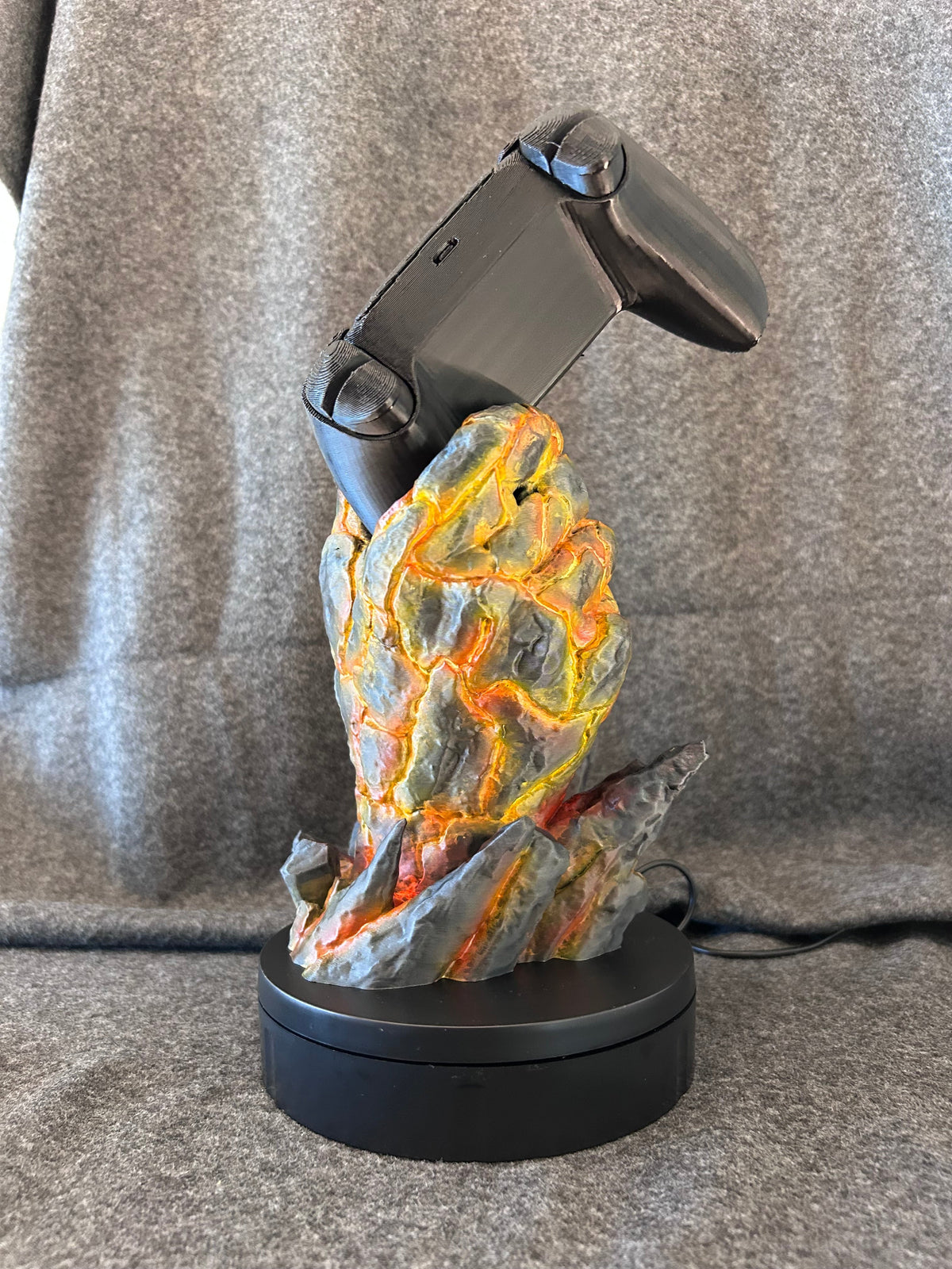 Close view of the painted basalt crust and molten core detail on the Emberfist stand.