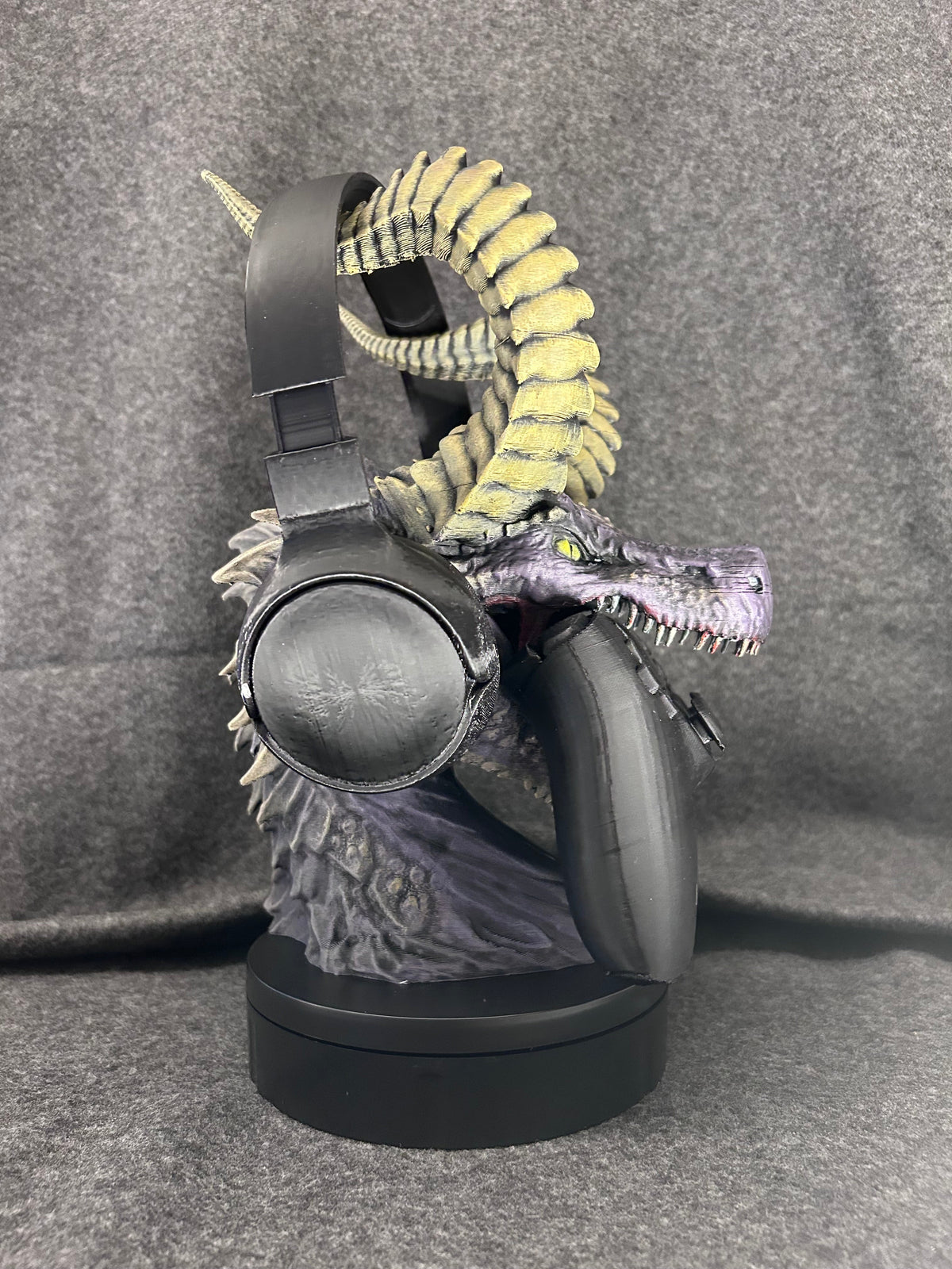 Hand-painted violet dragon bust holding a controller in its jaws and a headset on its curled yellow horns.
