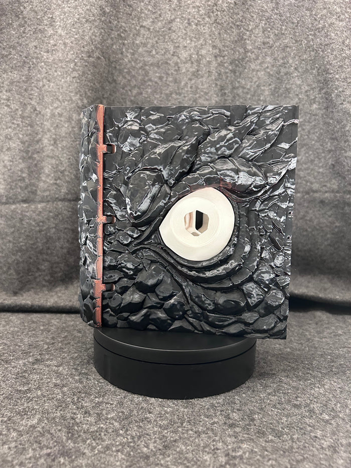 The Wyrmhoard dice case closed, showing the pale spiral shell set into the scaled lid.