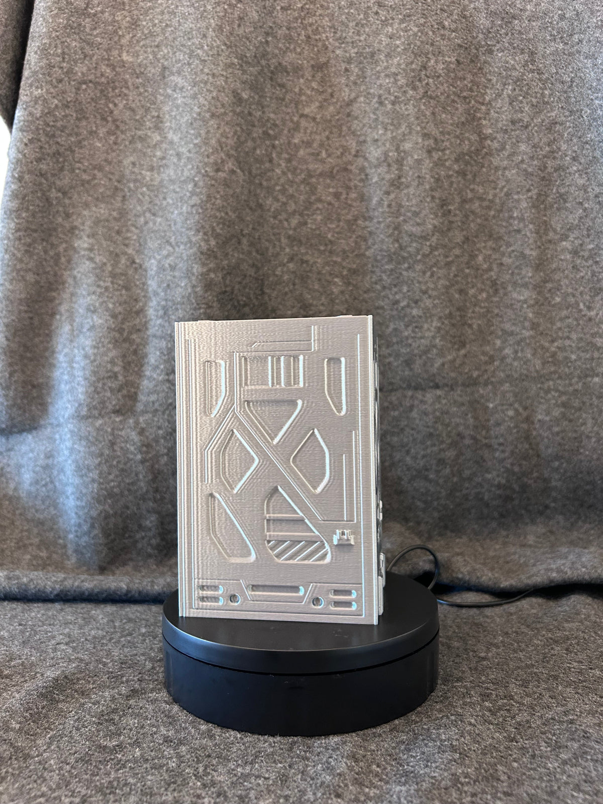 Sci-fi deck box printed in silver filament with panelled plating and a recessed skull sigil.