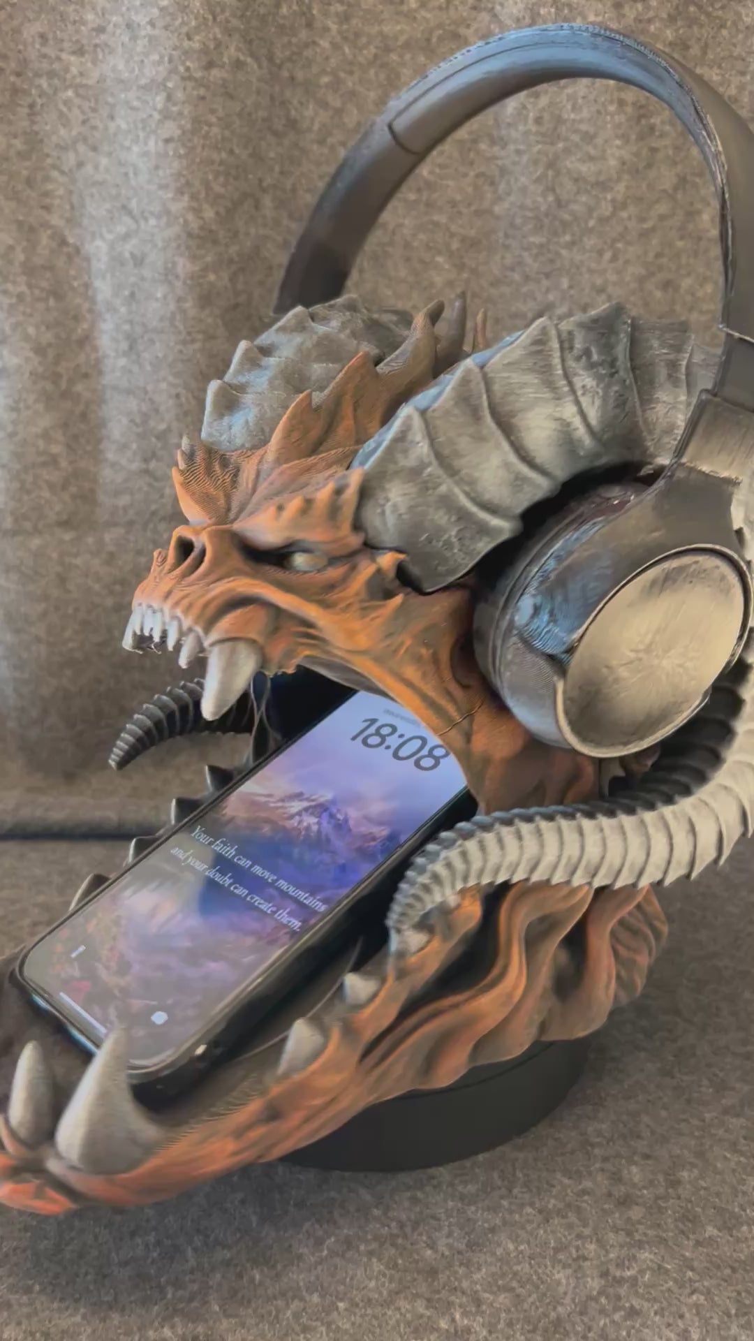 The Warden of the Hoard turning on a display stand, holding a headset on its horns and a phone in its jaws.