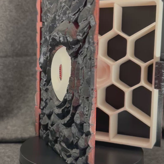The Wyrmhoard dice case turning on a display stand, showing the scaled faces and the spiral shell lid.