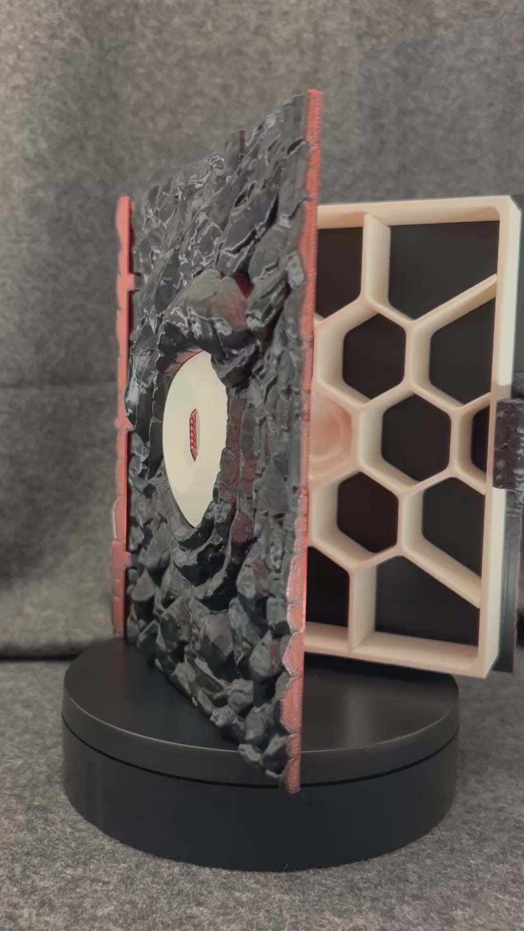 The Wyrmhoard dice case turning on a display stand, showing the scaled faces and the spiral shell lid.