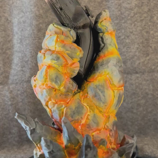 The Emberfist controller stand turning on a display stand, showing the glowing fissures in the painted basalt.