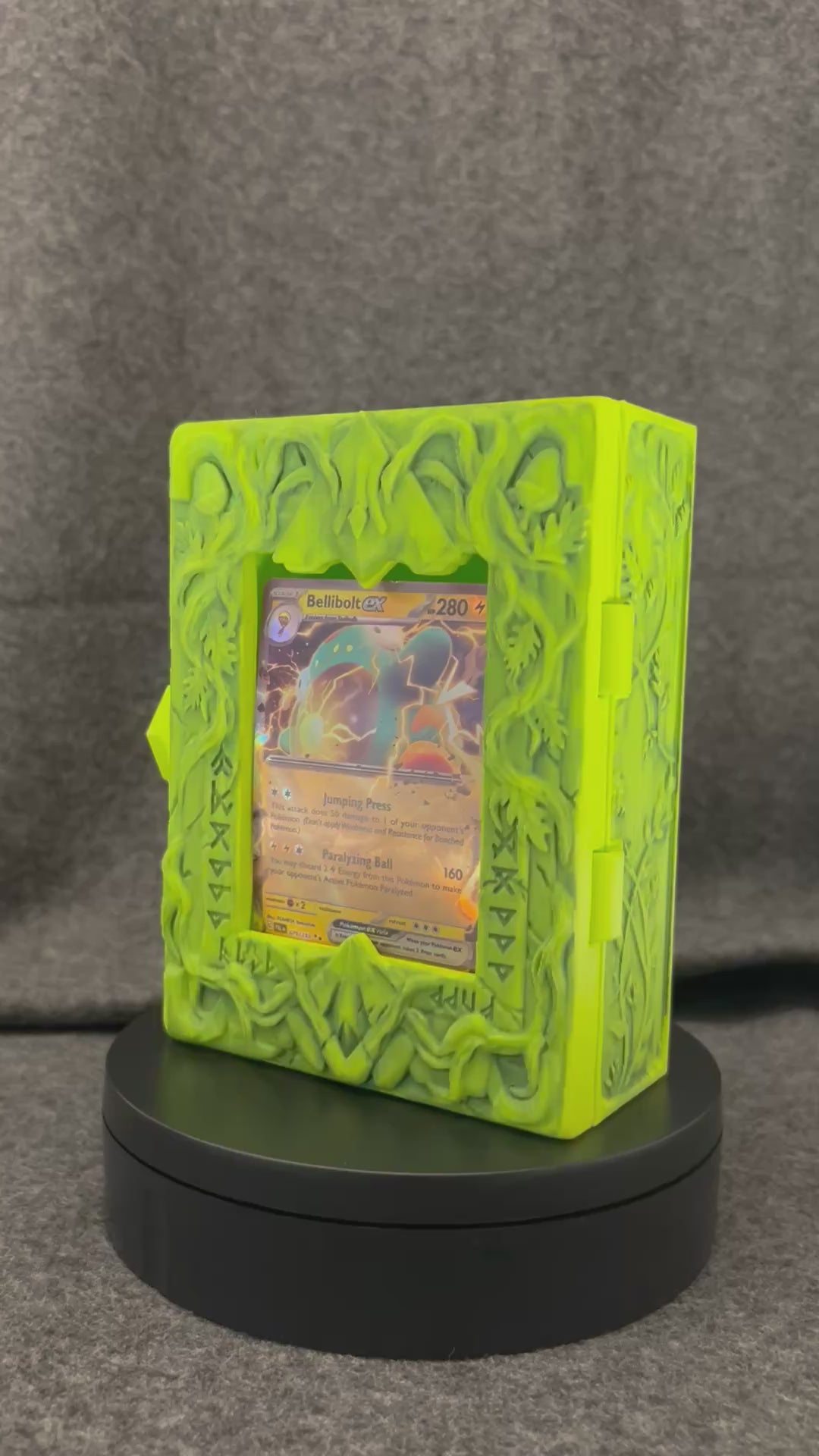 The Verdant Codex card display case turning on a display stand, showing the carved vine work.